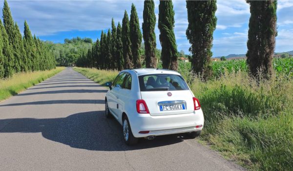 White Fiat 500 on a road trip in Tuscany Italy with typical landscape