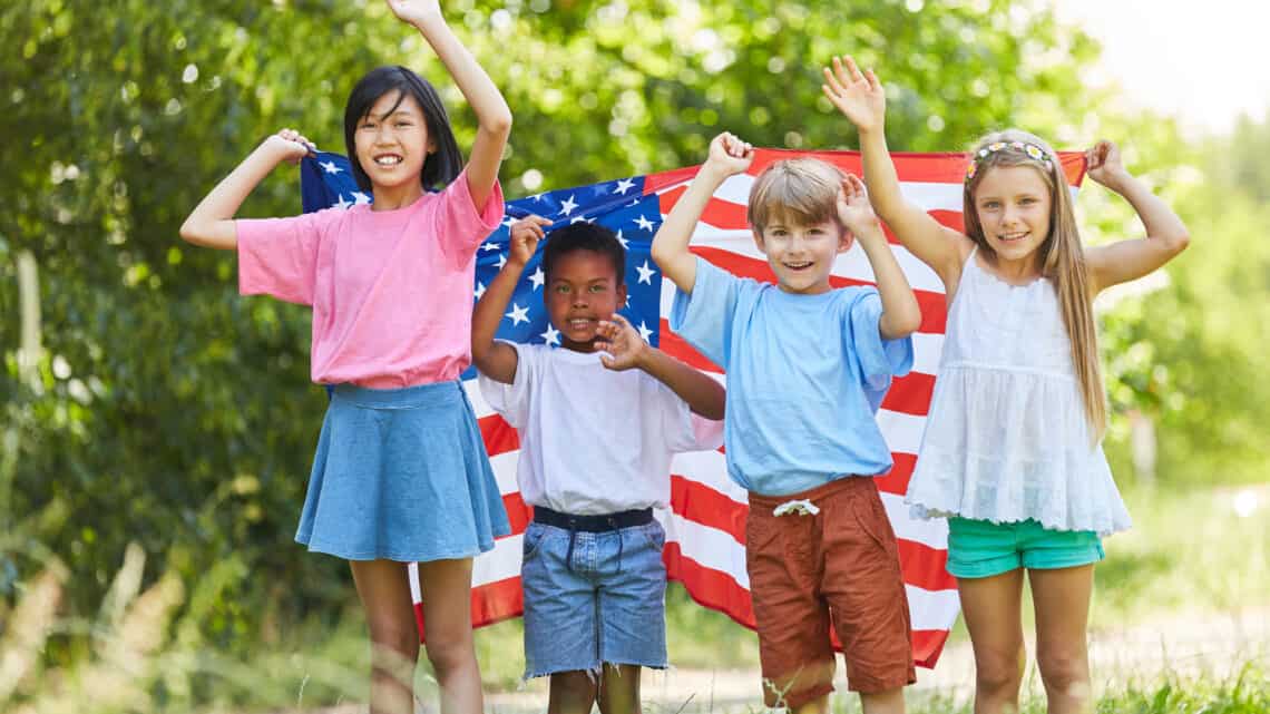 Multicultural group of kids waving with US flag on Labor Day