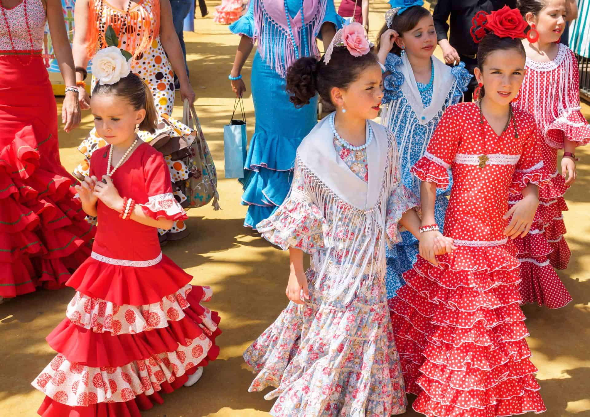 Spanish girls in traditional dress walking alongside Casitas at the Seville Fair called Feria de Abril