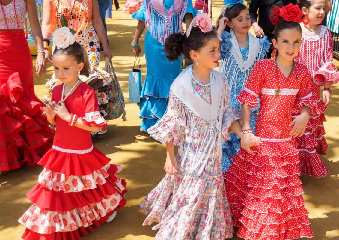 Spanish girls in traditional dress walking alongside Casitas at the Seville Fair called Feria de Abril