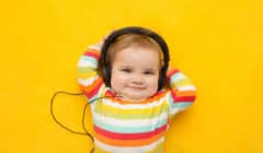Baby equipped with headphones on a yellow background