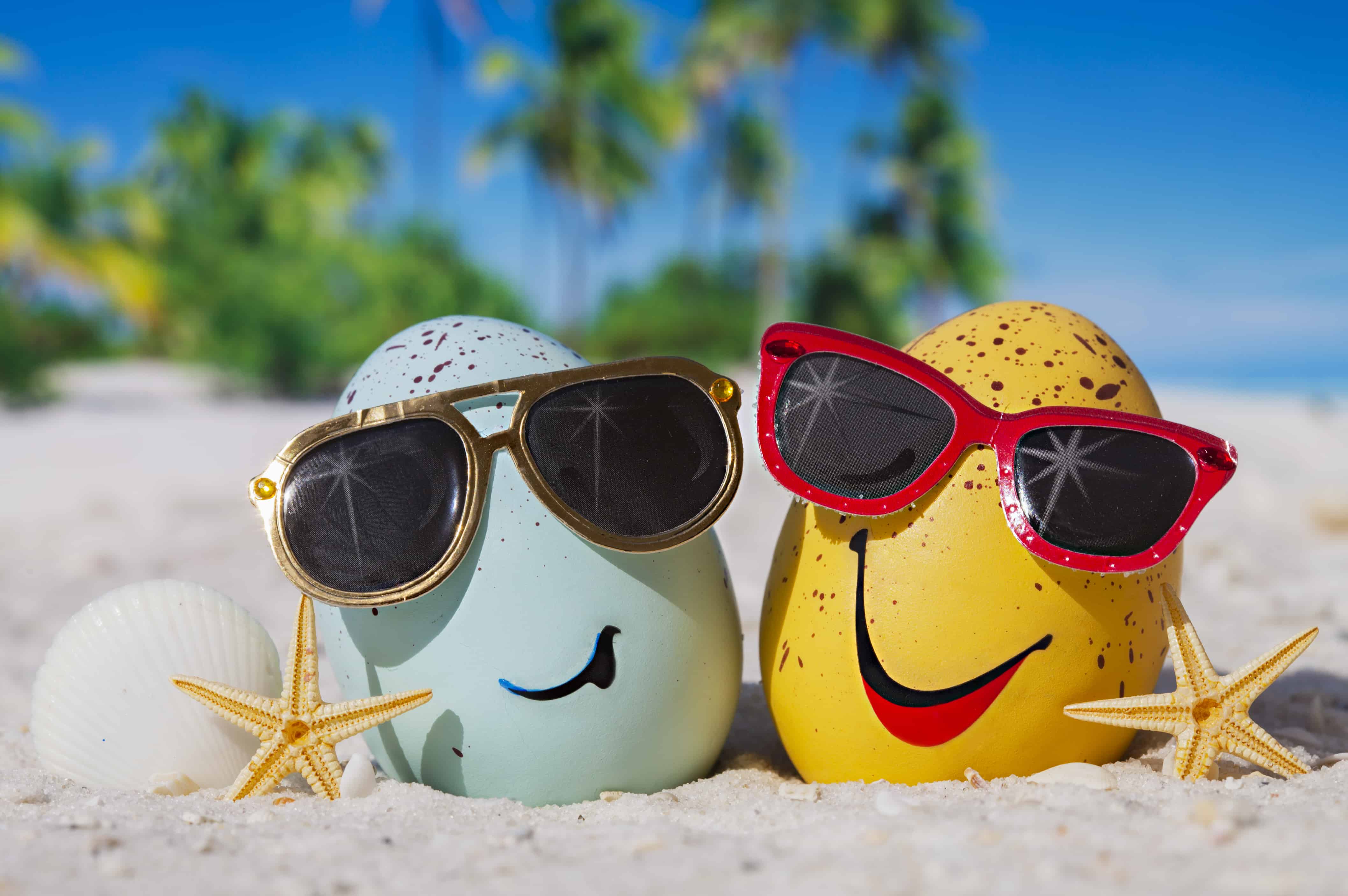 Two Easter eggs wearing sunglasses on a beach