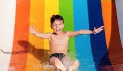 Boy having fun while sliding down a water slide in a water park