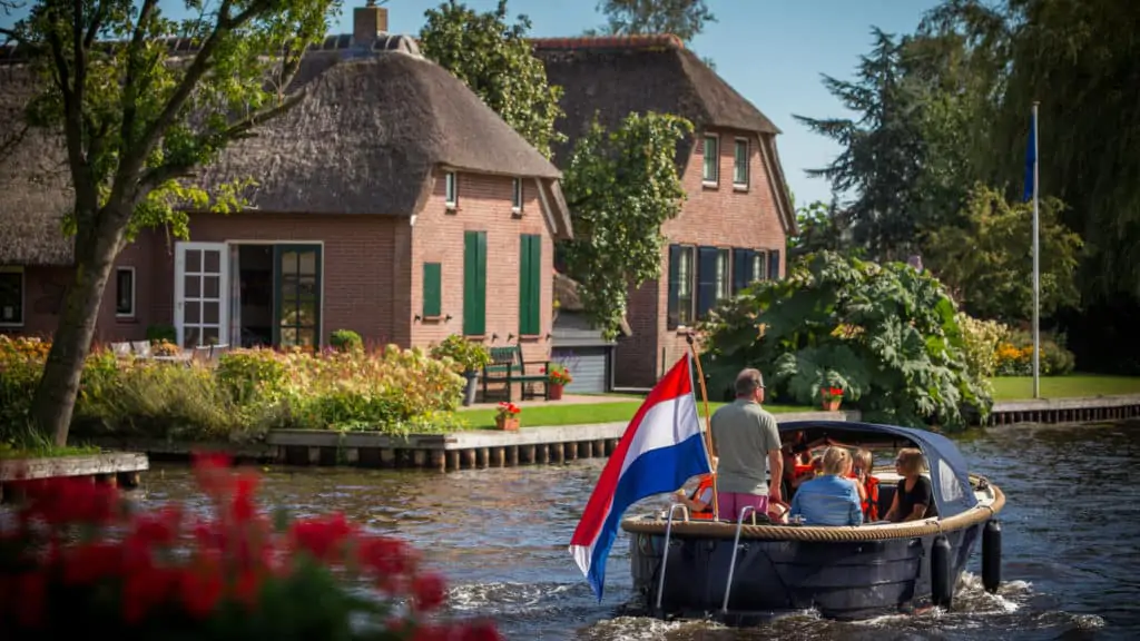 Family taking a boat trip in Giethoorn, Holland, the Netherlands, with typical houses in the background
