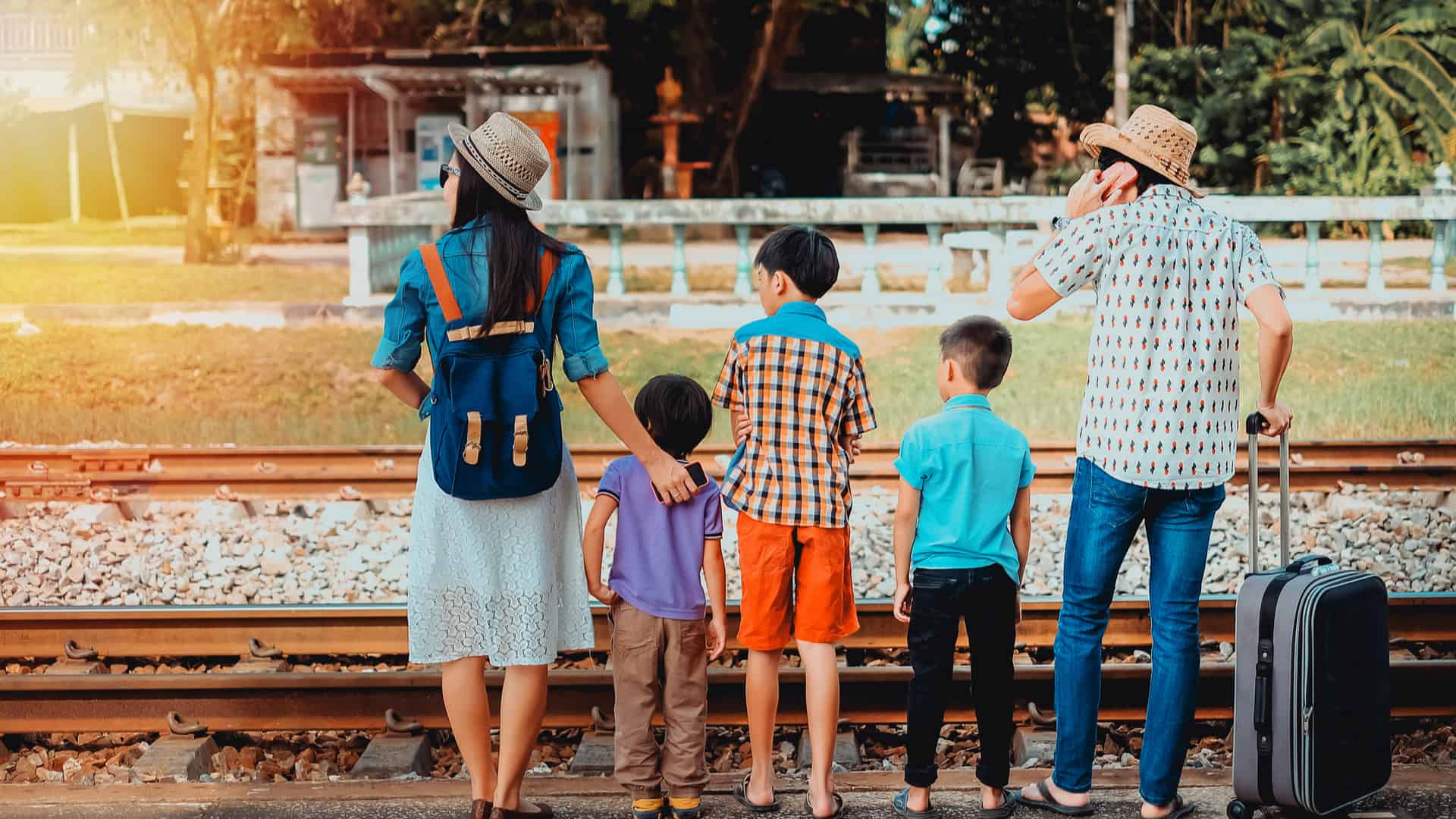 Family with three children waiting for a train right next to the tracks
