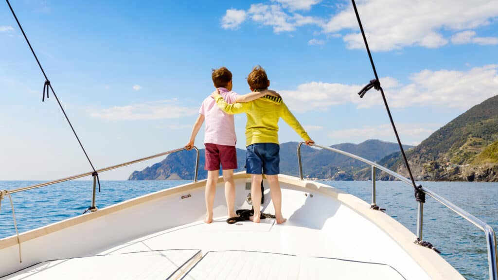 Two boys standing on deck of a sailing boat looking towards the coast in Croatia