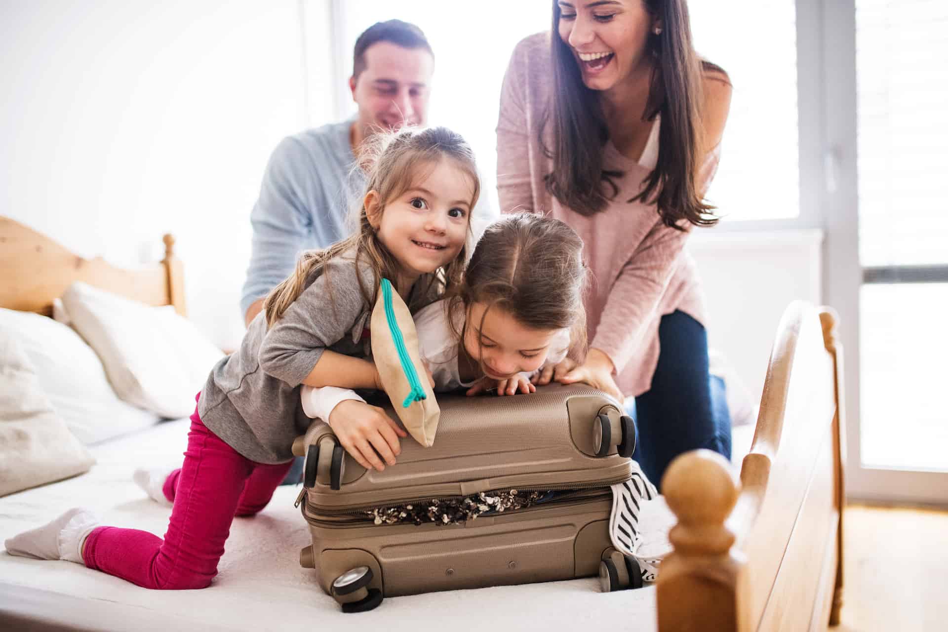 Parents with two kids over a suitcase getting them ready for a trip abroad
