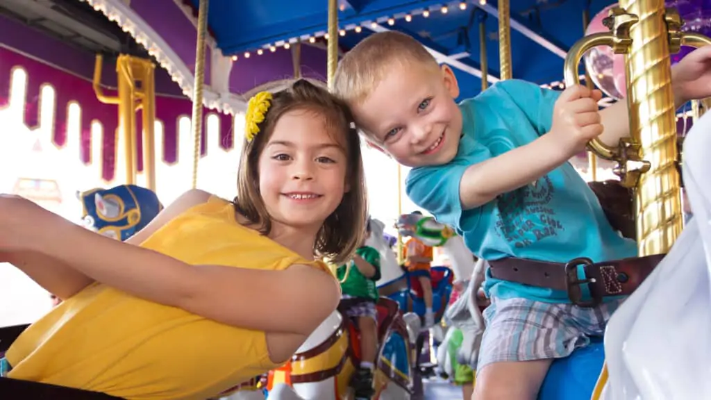 A boy and a girl having fun in a carousel at an amusement park carnival in Europe