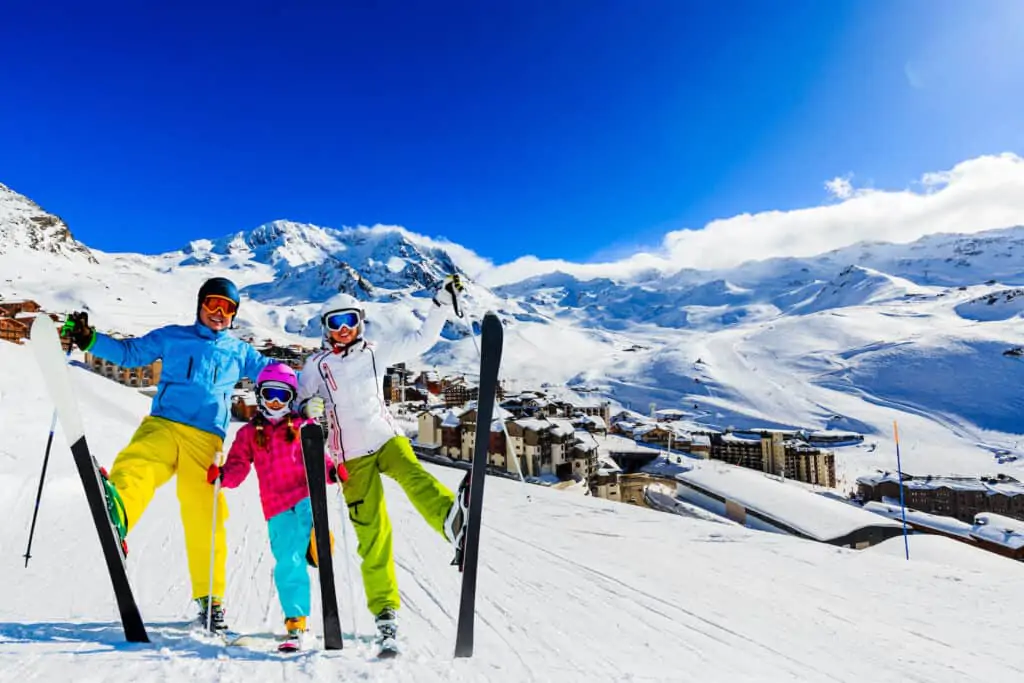 Happy family skiing in the French Alps with blue sky and lots of snow in the background