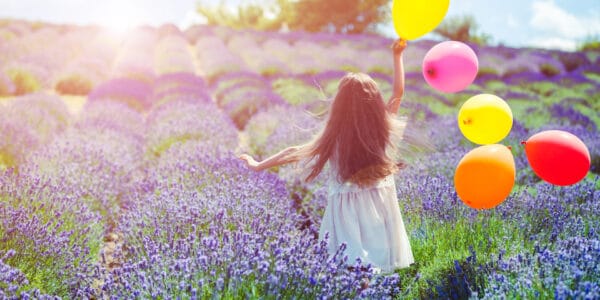 A girl with balloons running through the lavender fields in Provence, France.