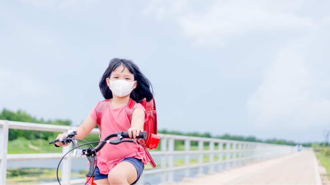 Asian girl riding a bicycle with a mask in a post COVID-19 world