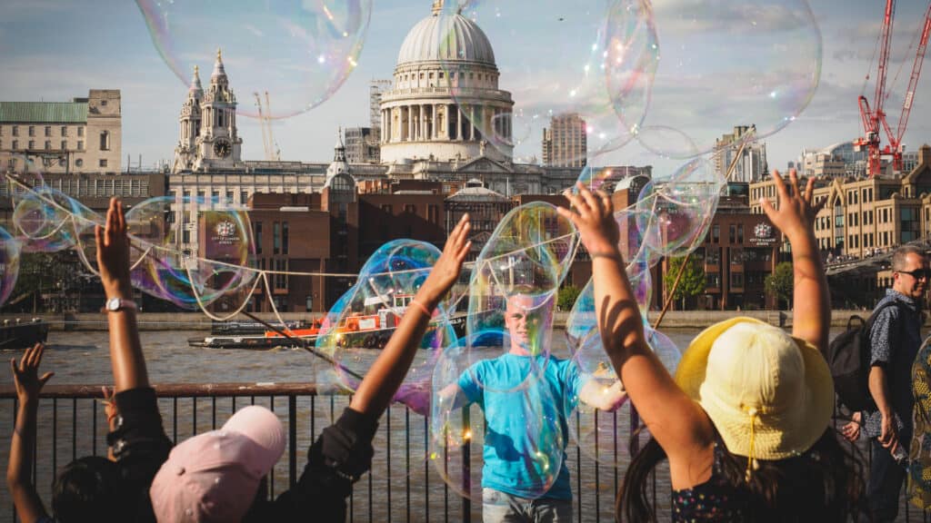 Happy kids having fun with soap bubbles on South Bank of the Thames river, with St. Paul's Cathedral in London, U.K.