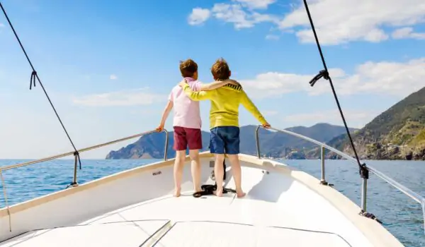 Two boys standing on deck of a sailing boat looking towards the coast in Croatia