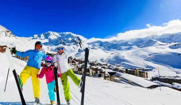 Happy family skiing in the French Alps with blue sky and lots of snow in the background