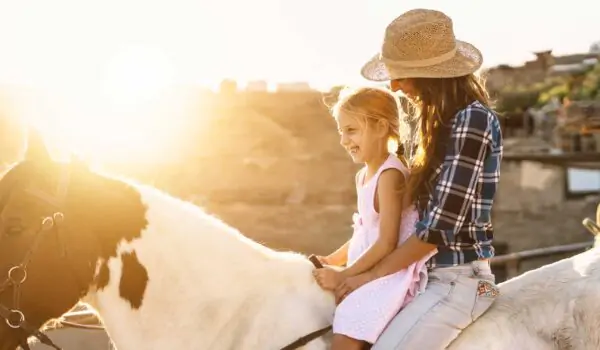 Happy family with mother and daughter on a horse on a farm in Texas, USA